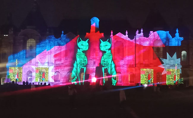 A large façade is projection mapped with images of stylized cats.