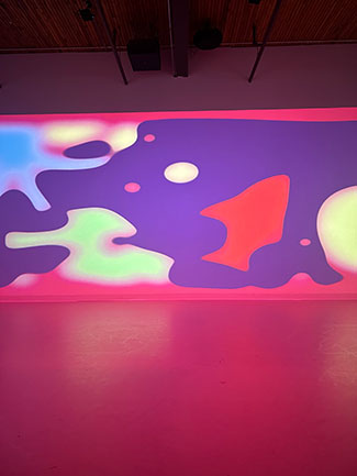 An abstract image in shades of red, purple, and blue is projected onto a wall.