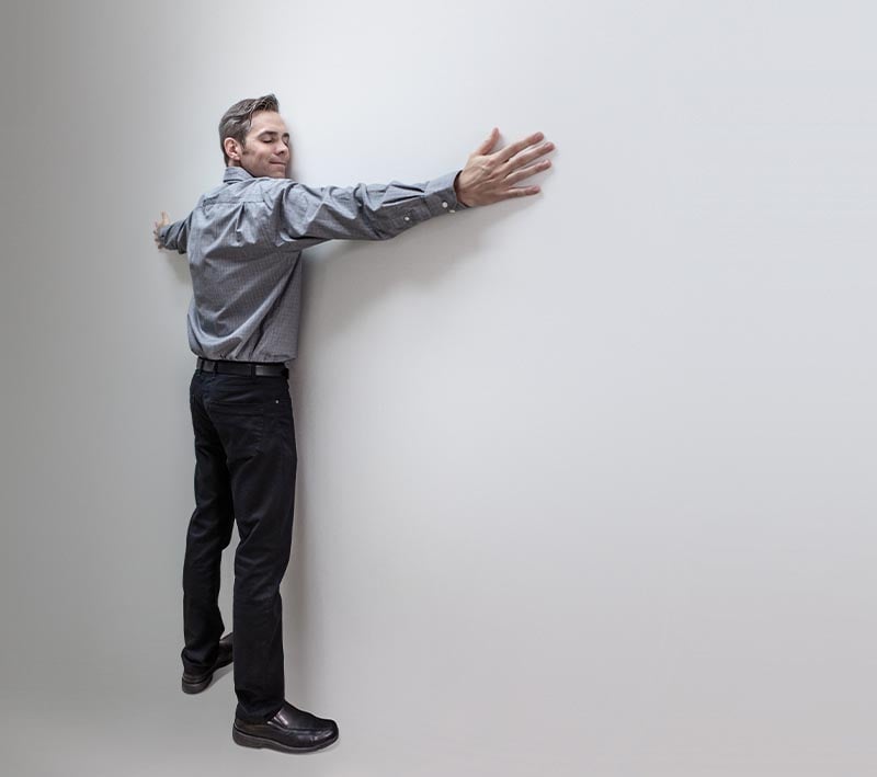 A man standing with his arms spread touching a wall