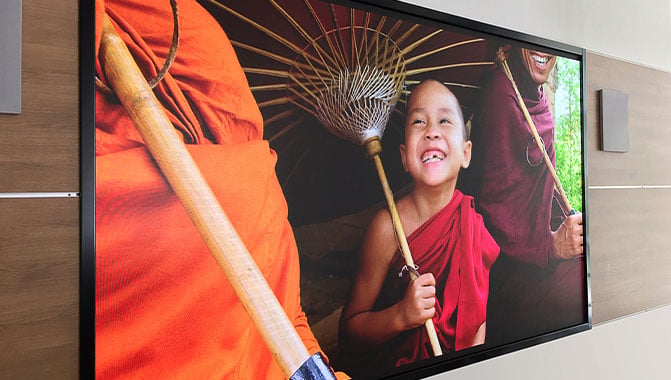 A video wall showing an image of a smiling child in a red robe and holding a bamboo umbrella. 