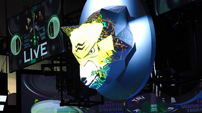 A 3D wolf head is projection-mapped in yellow, black, and white.