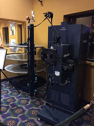 Large, tall film projector flanked by a film handling system