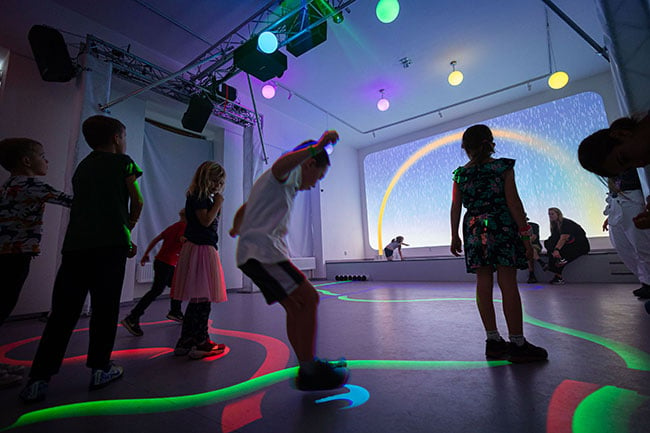 Children jumping on projected lines on a floor.