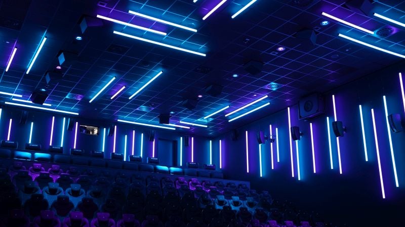 A dark and empty movie theatre with blue lighting.
