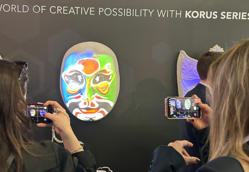 People photograph a projection mapped mask.