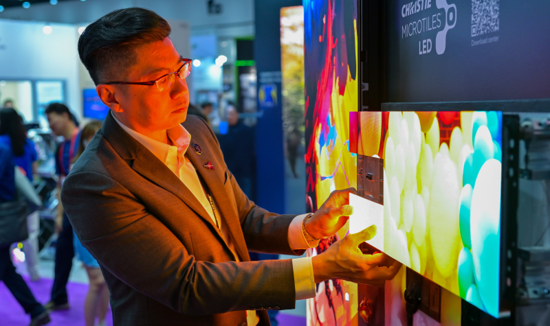 A man removes an LED tile on a display at a tradeshow.