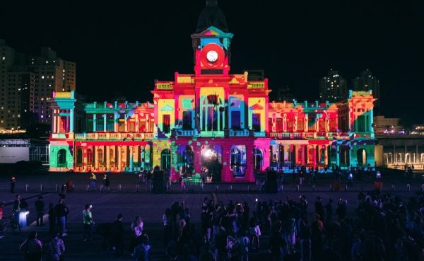 The fa&ccedil;ade of a large building is projection mapped with vibrant colors.