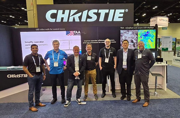 A group of Christie employees standing in front of a Chirstie event booth