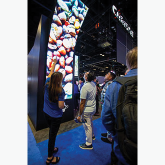 A Christie employee showing someone a tall MicroTiles LED video wall.