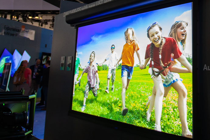 Screen with projection of a group of white children playing outside on green grass 
