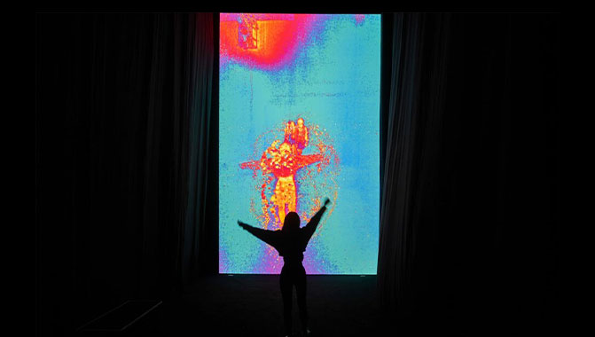 Silhouette of person in front of blue, red, and orange heat map projection mapping installation